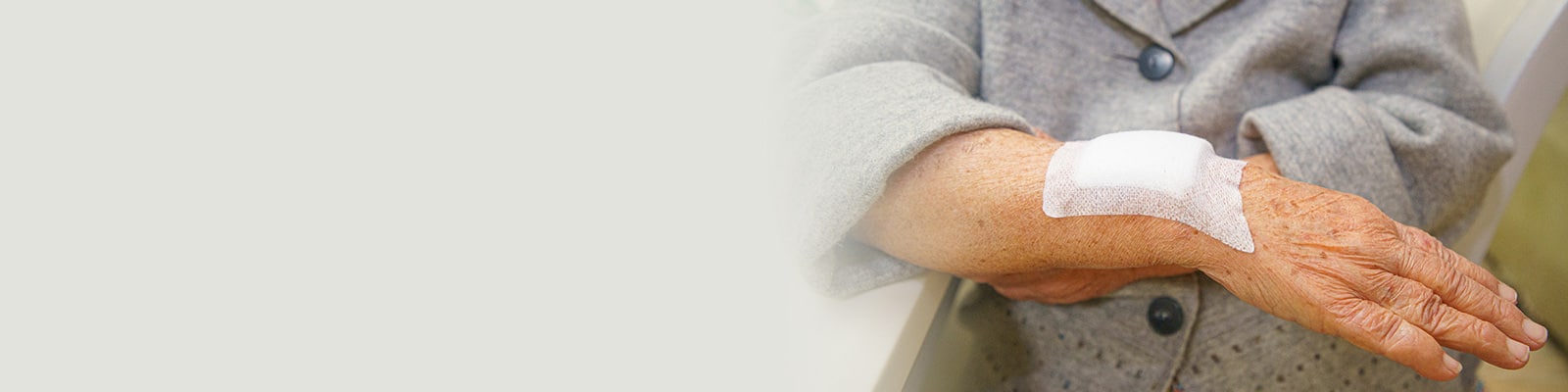 An elderly residents hand with bandages over a wound