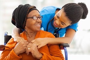A senior embracing and smiling at her nurse.